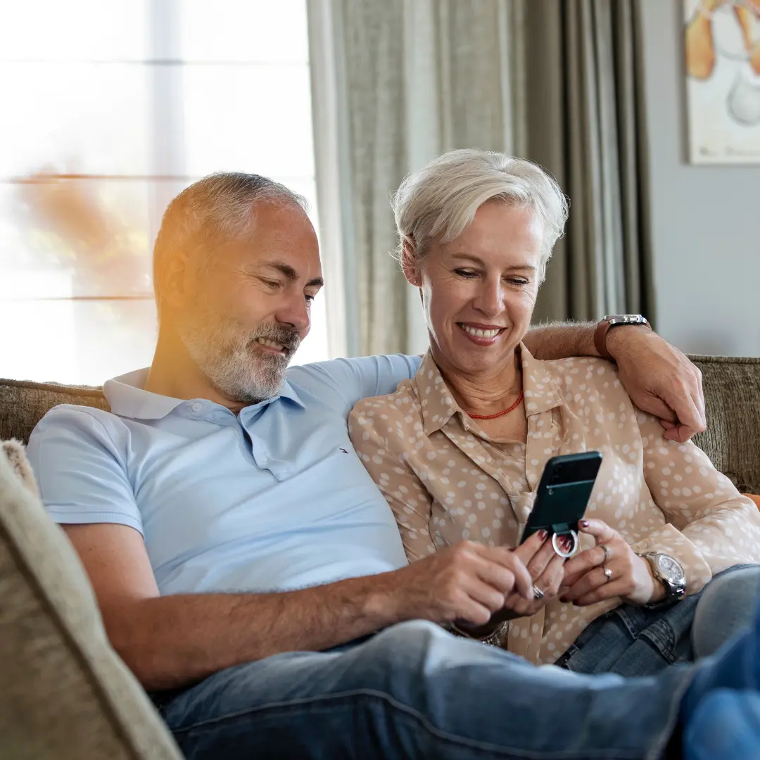 Man en vrouw zitten op de bank kijkend naar een mobiel
