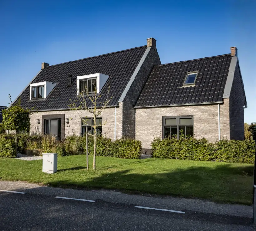 Vooraanzicht van een vrijstaande woning met aanbouw en twee dakkapellen