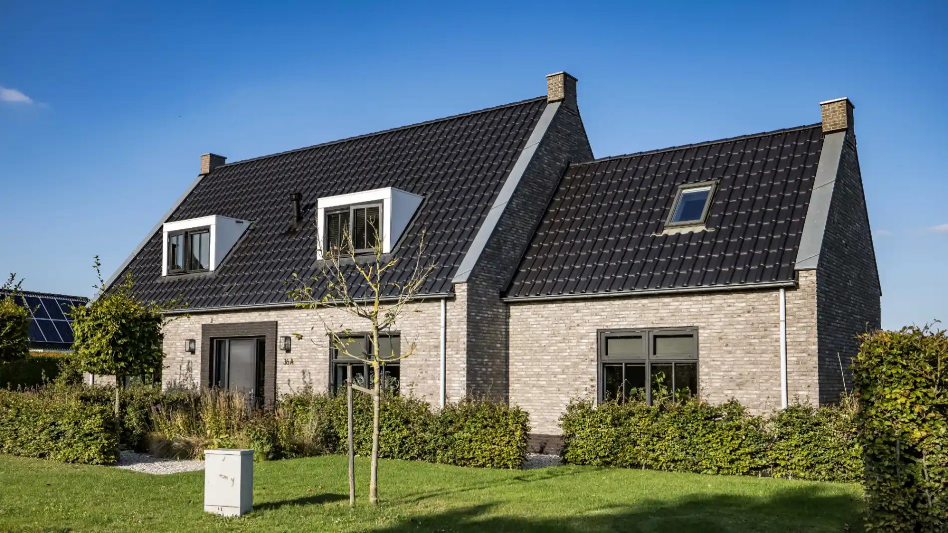 Vooraanzicht van een vrijstaande woning met aanbouw en twee dakkapellen