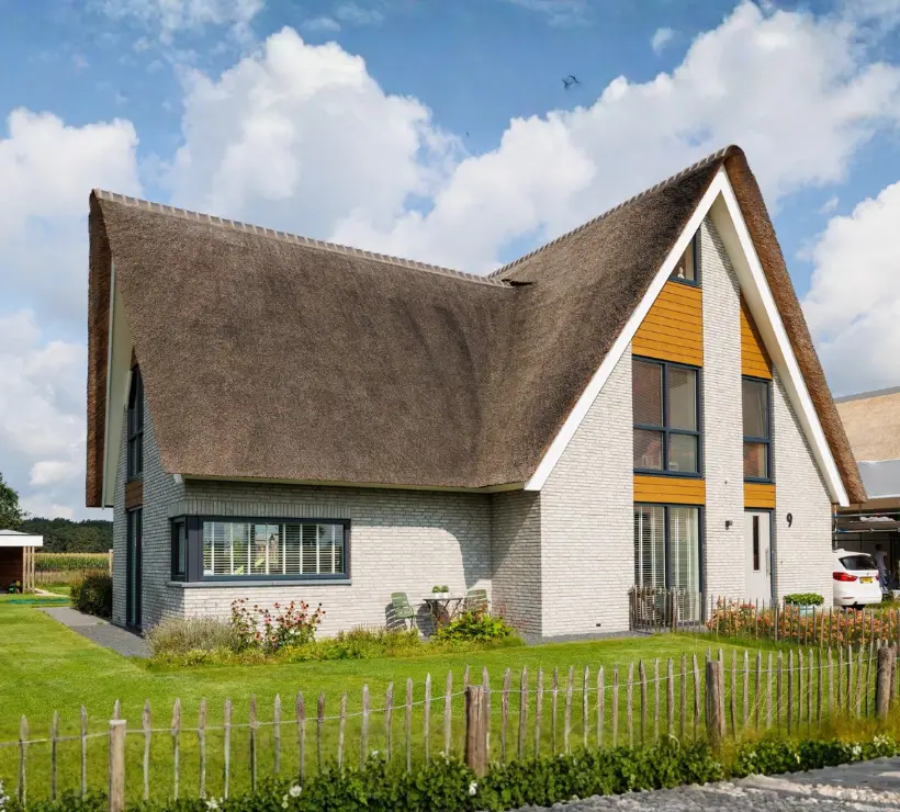 Voorgevel van een vrijstaande woning met rieten dak en aanbouw