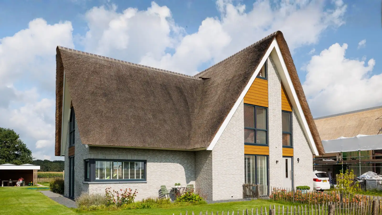 Voorgevel van een vrijstaande woning met rieten dak en aanbouw