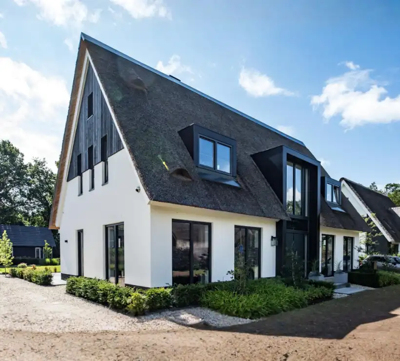 Voorzijde van een witte vrijstaande woning met rieten kap