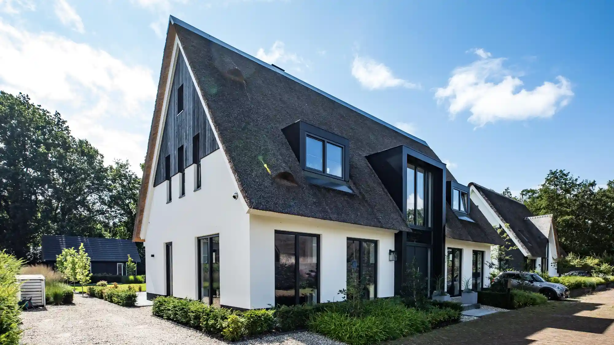 Voorzijde van een witte vrijstaande woning met rieten kap