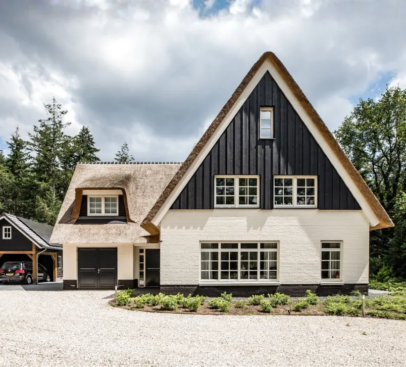 Vooraanzicht van een wit landhuis met rieten kap