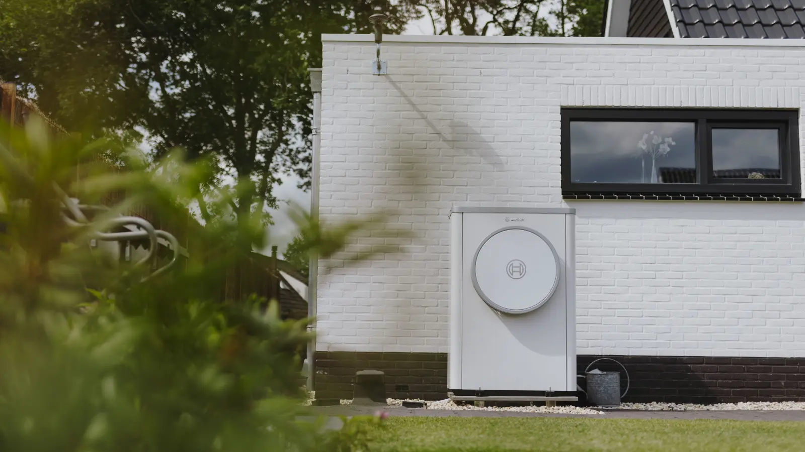 Warmtepomp staat voor een witte aanbouw van een woning