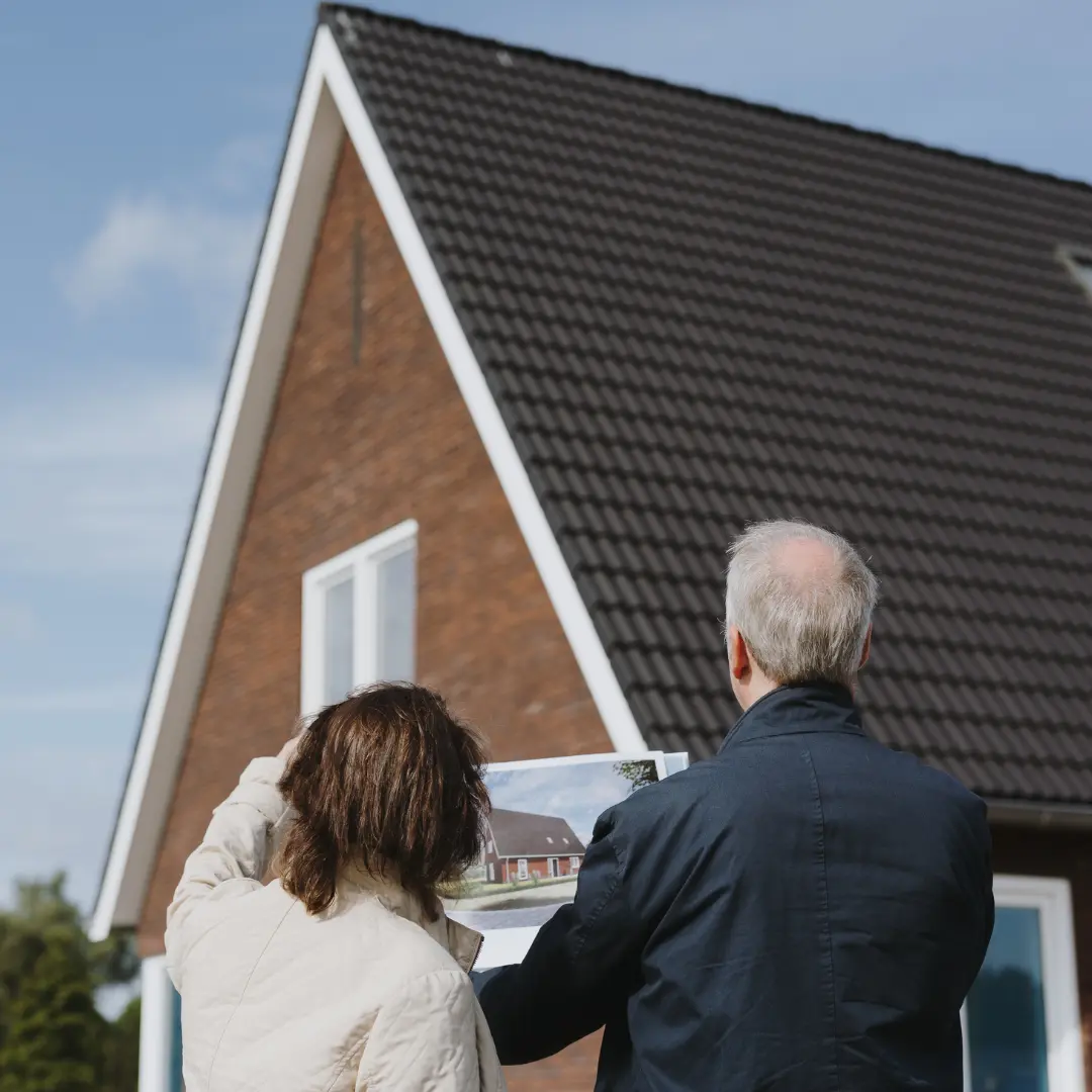 Man en vrouw staan voor hun woning met een schetstekening in hun hand