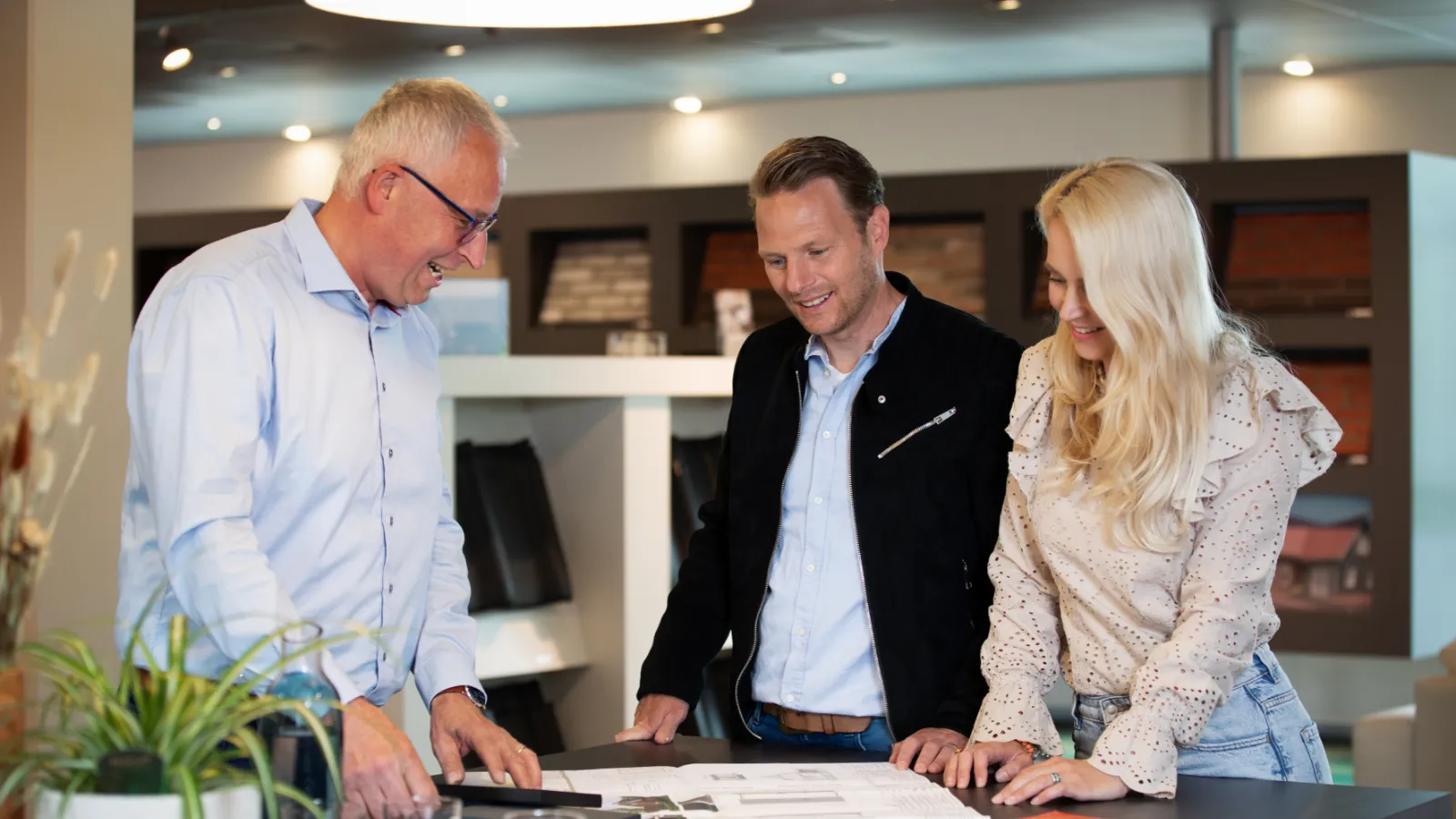 Adviseur in gesprek met man en vrouw. Ze kijken naar een plattegrond op een bureau