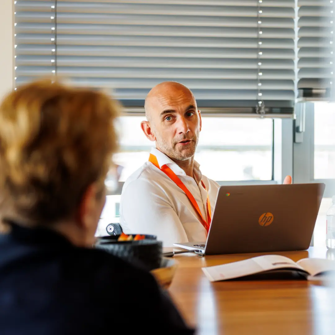Een adviseur van SelektHuis met laptop in gesprek met een klant