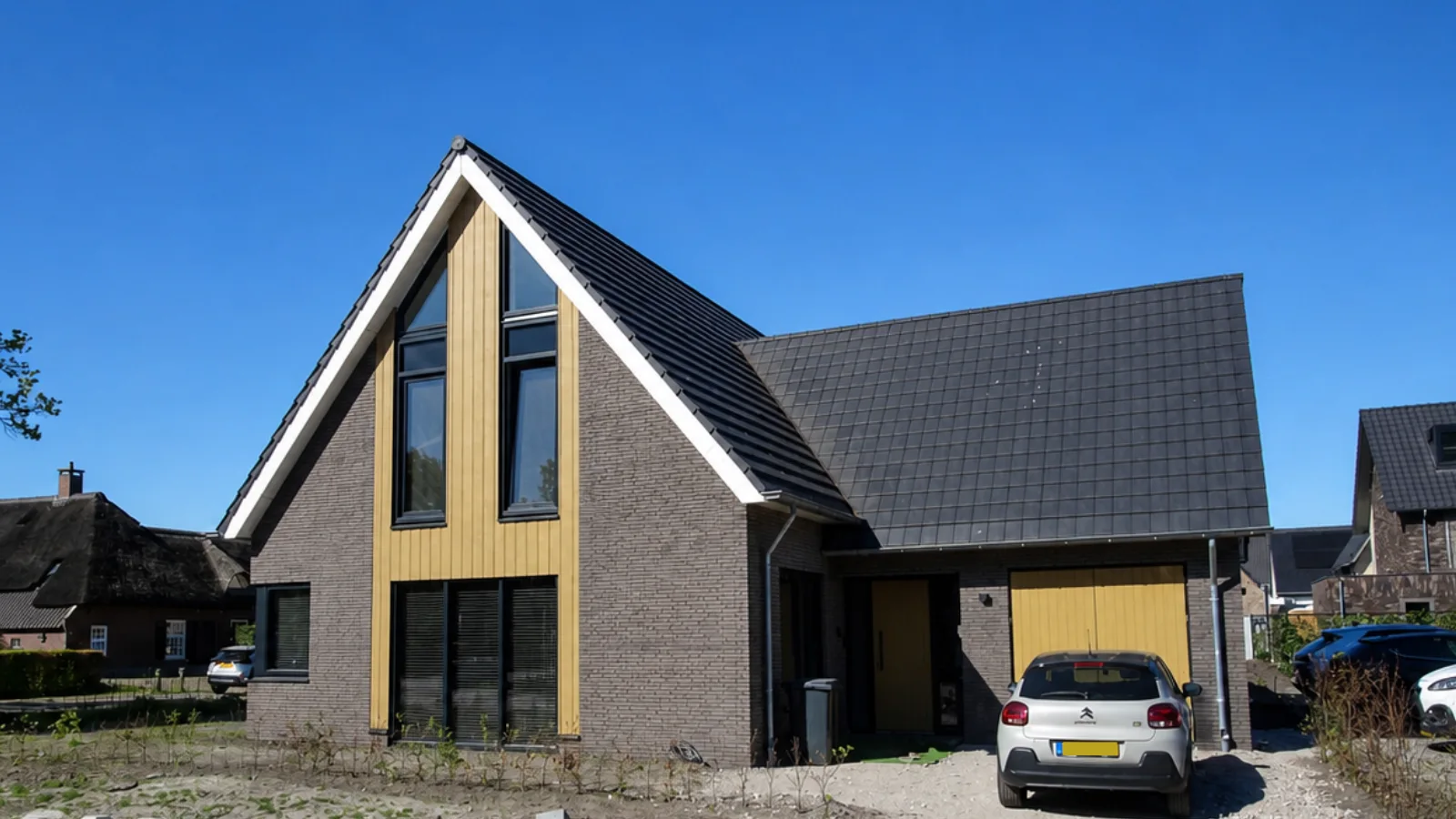 Vrijstaande woning met donkere gevelstenen en lichte houtengevelbekleding