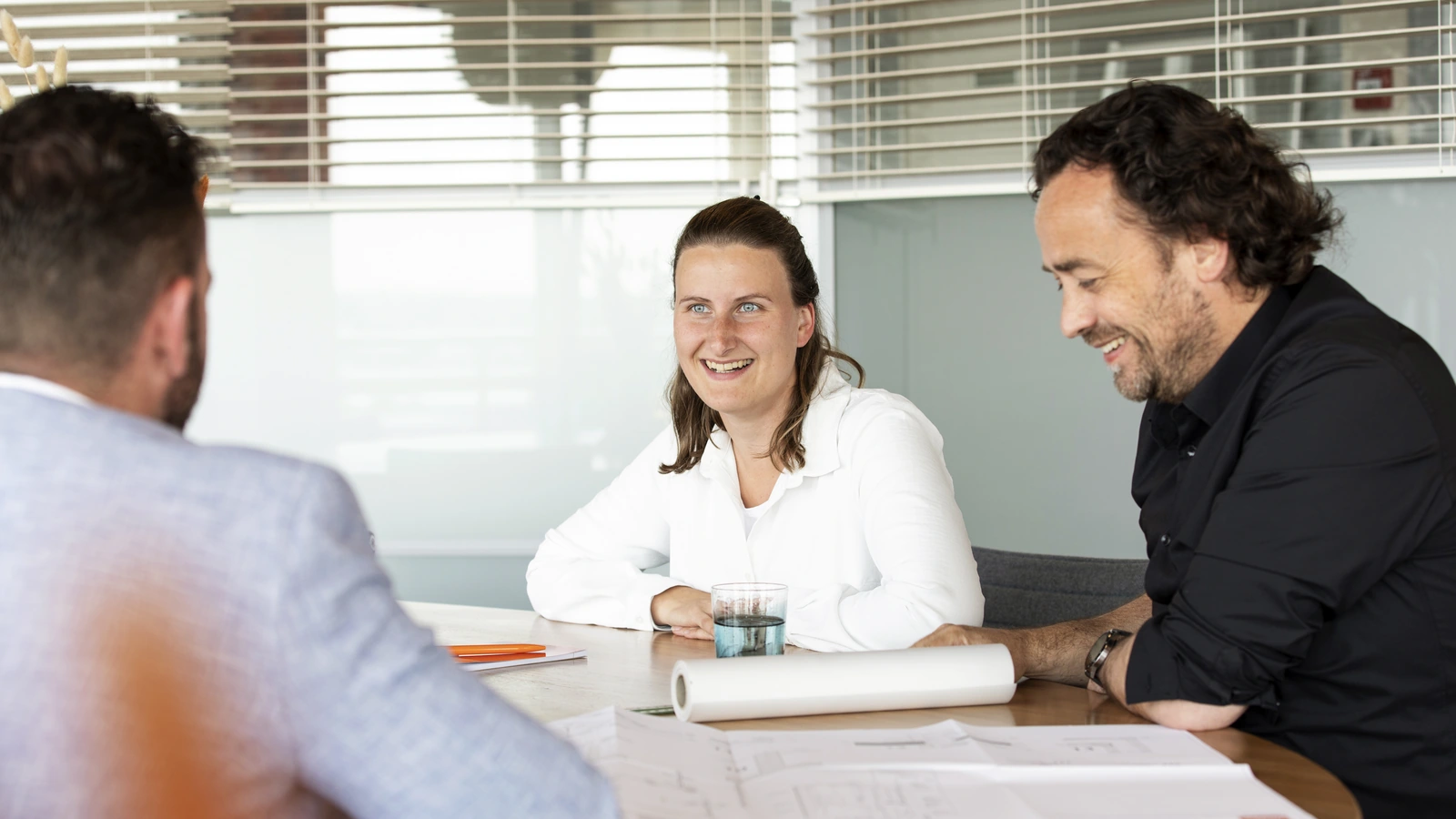 Drie mensen in gesprek aan een tafel