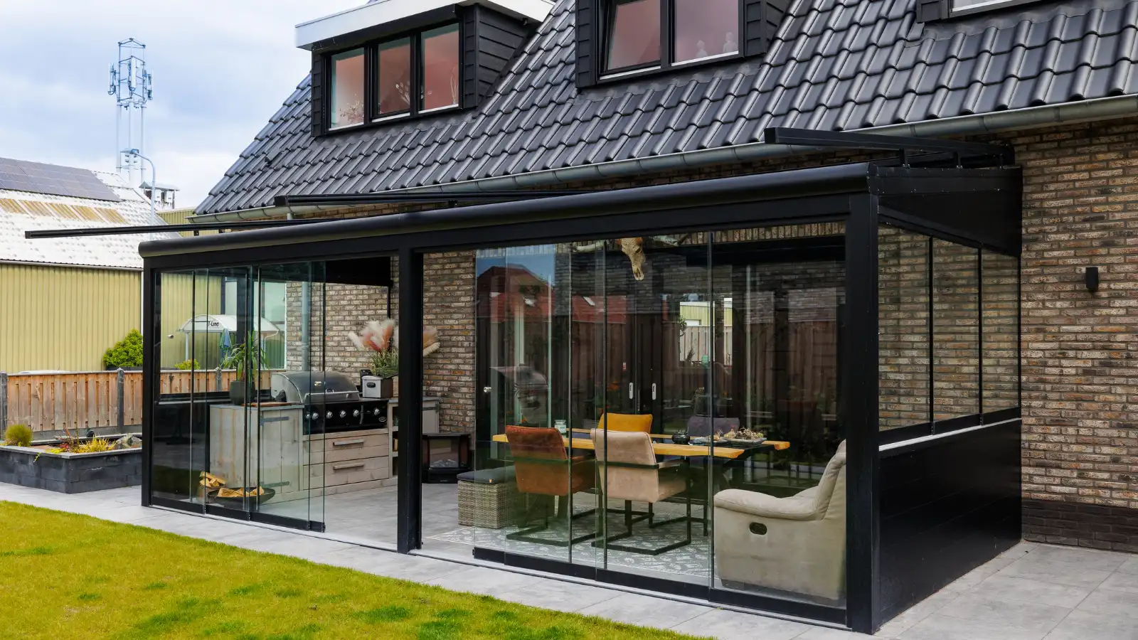 Glazen veranda met zwarte details vast aan een woning