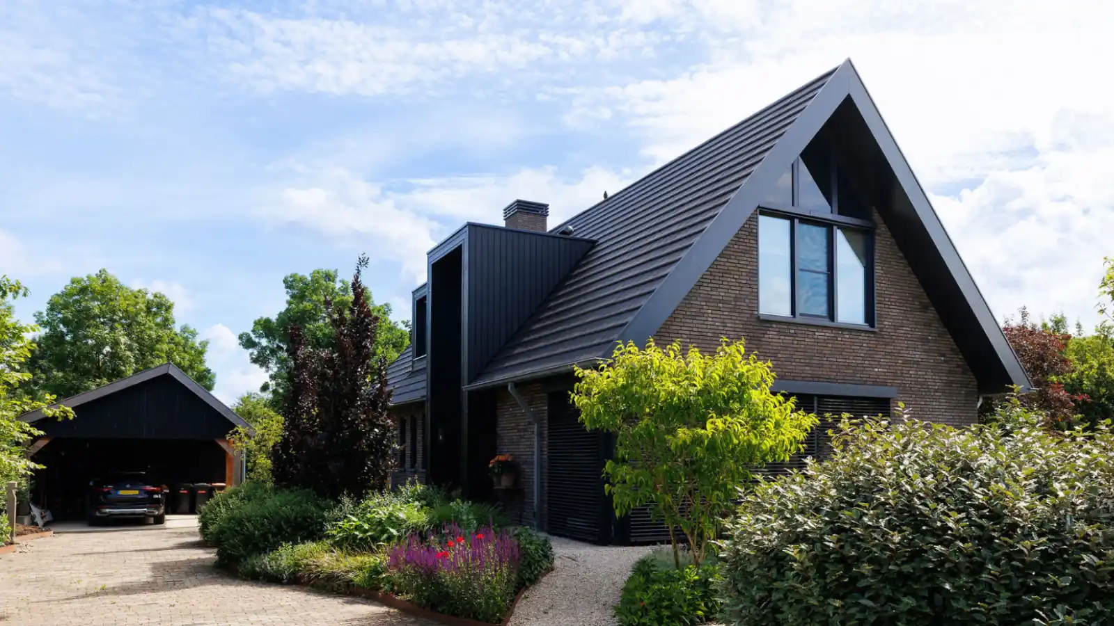 Vrijstaande schuurwoning met donkere gevelstenen, houten gevelbekleding en risaliet