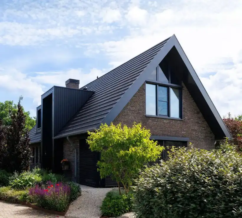 Vrijstaande schuurwoning met donkere gevelstenen, houten gevelbekleding en risaliet