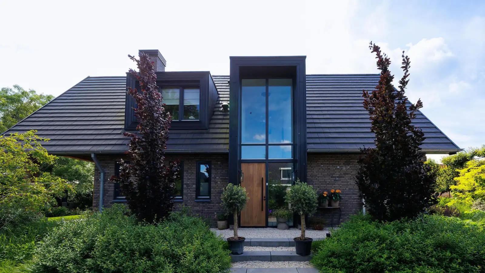 Vrijstaande schuurwoning met donkere gevelstenen, houten gevelbekleding en risaliet