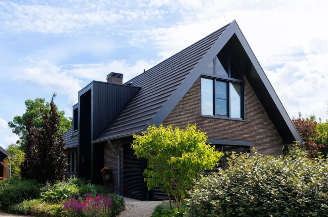 Vrijstaande schuurwoning met donkere gevelstenen, houten gevelbekleding en risaliet