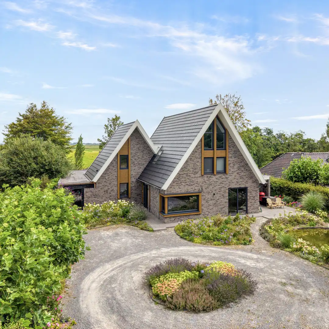Vrijstaande woning het aanbouw. Grijze gevelstenen en houten gevelbekleding