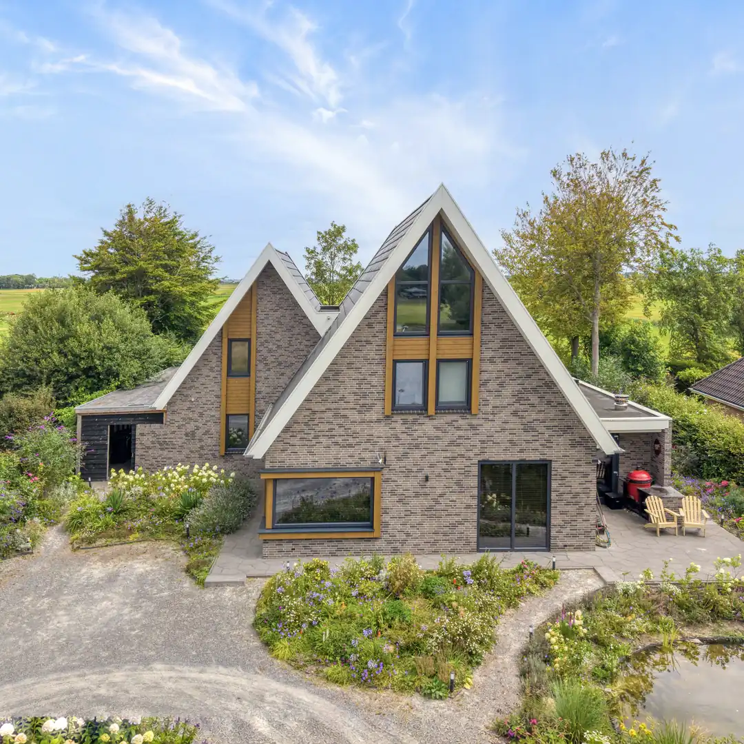 Vrijstaande woning het aanbouw. Grijze gevelstenen en houten gevelbekleding