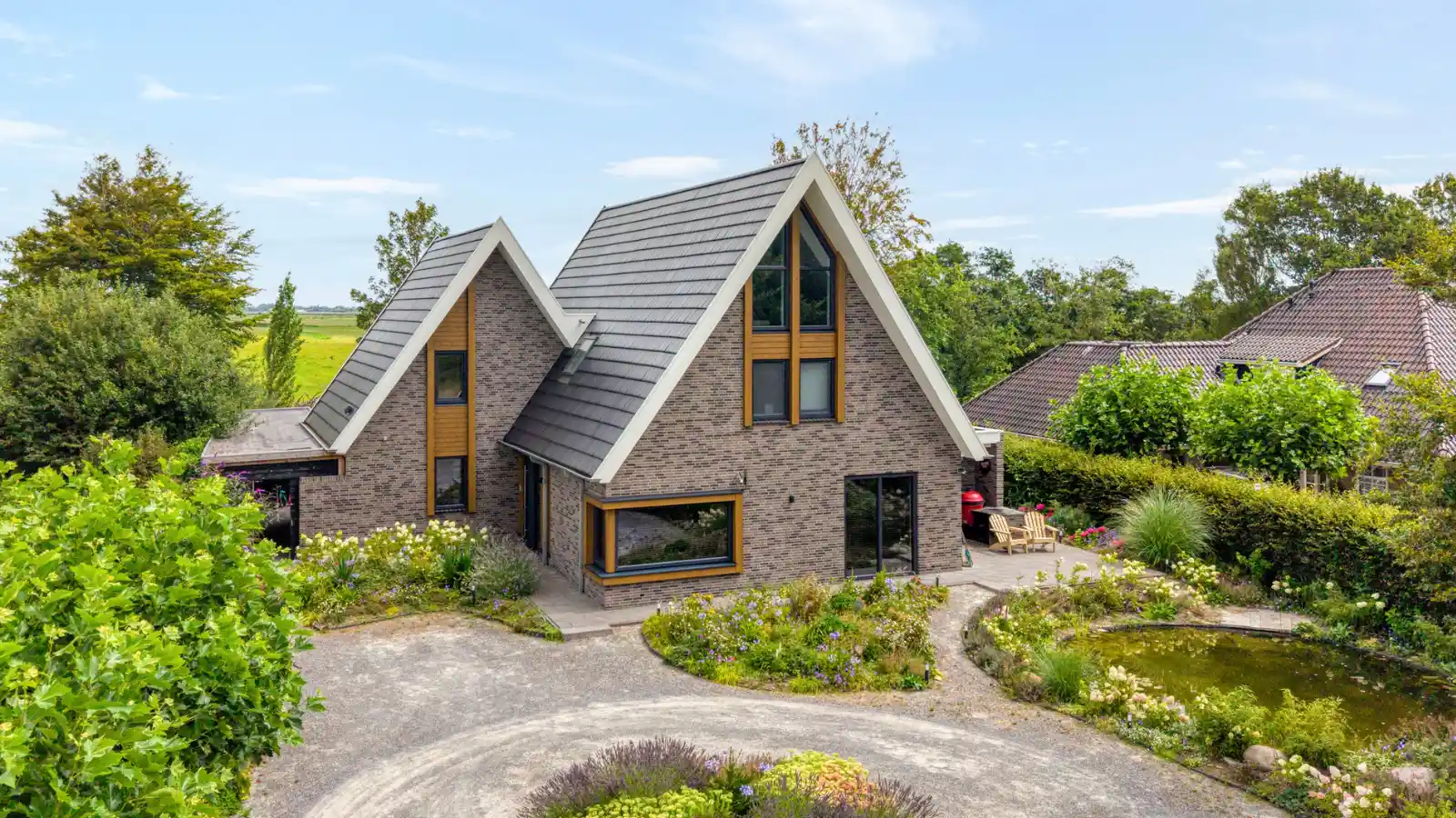 Vrijstaande woning met twee gevelpunten. Grijze gevelstenen en houten gevelbekleding