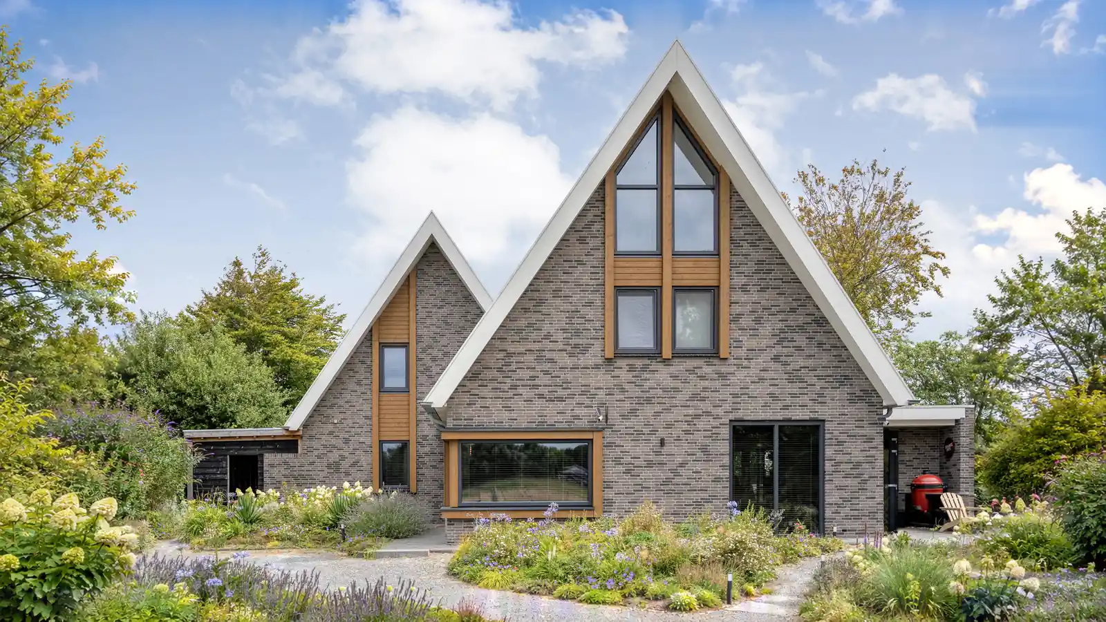 Vrijstaande woning met twee gevelpunten. Grijze gevelstenen en houten gevelbekleding