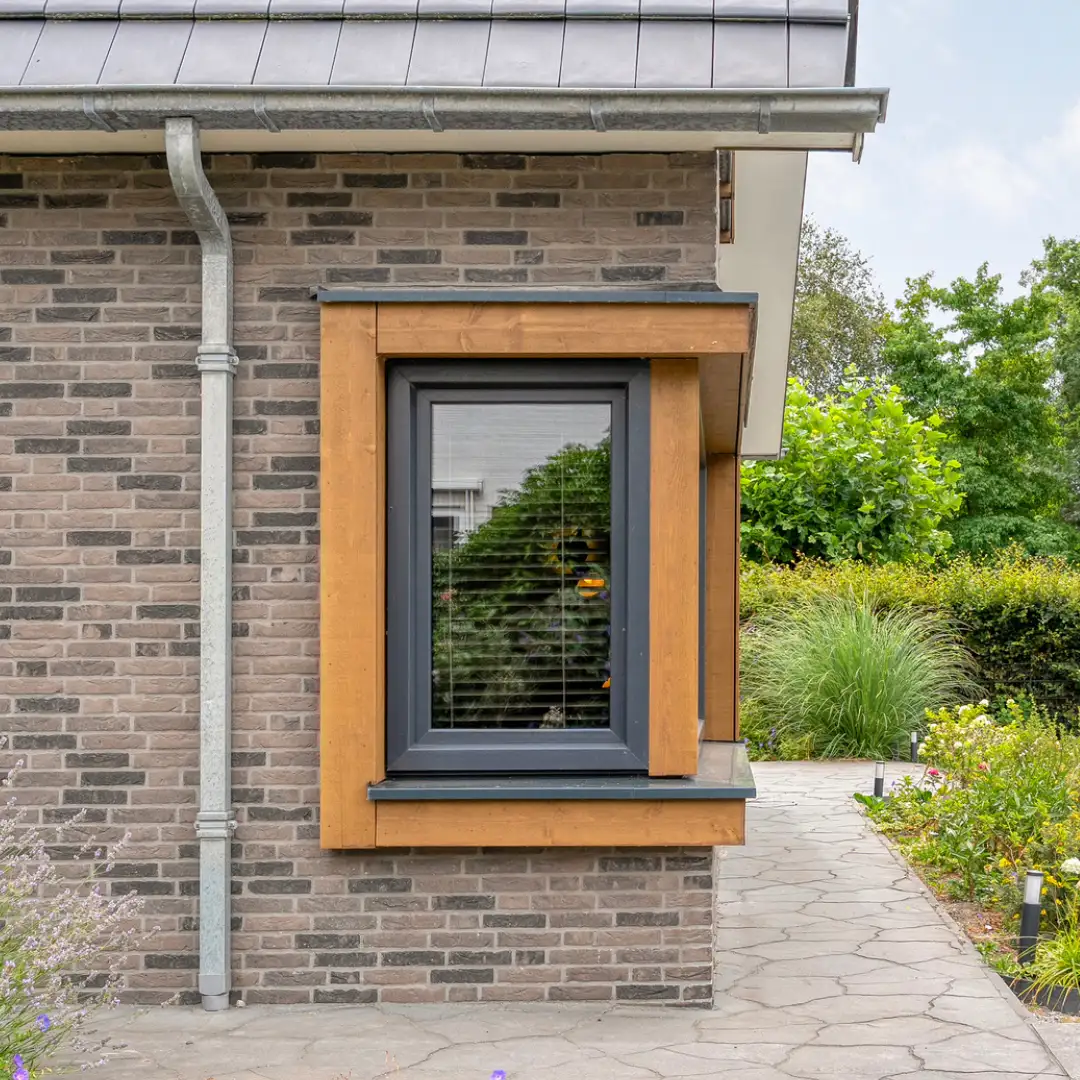 Hoekkozijn met houten omlijsting in een grijze gevel