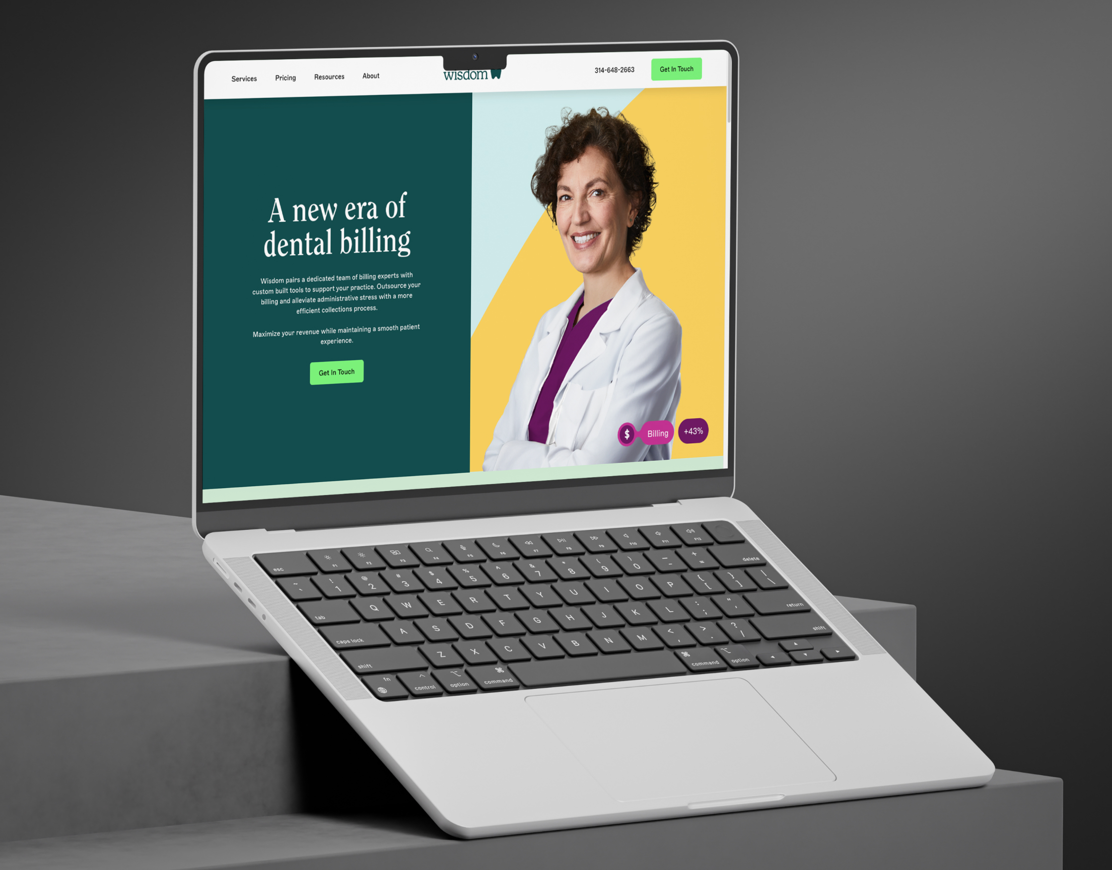 Wisdom dental billing homepage displayed on a white MacBook set on grey concrete steps