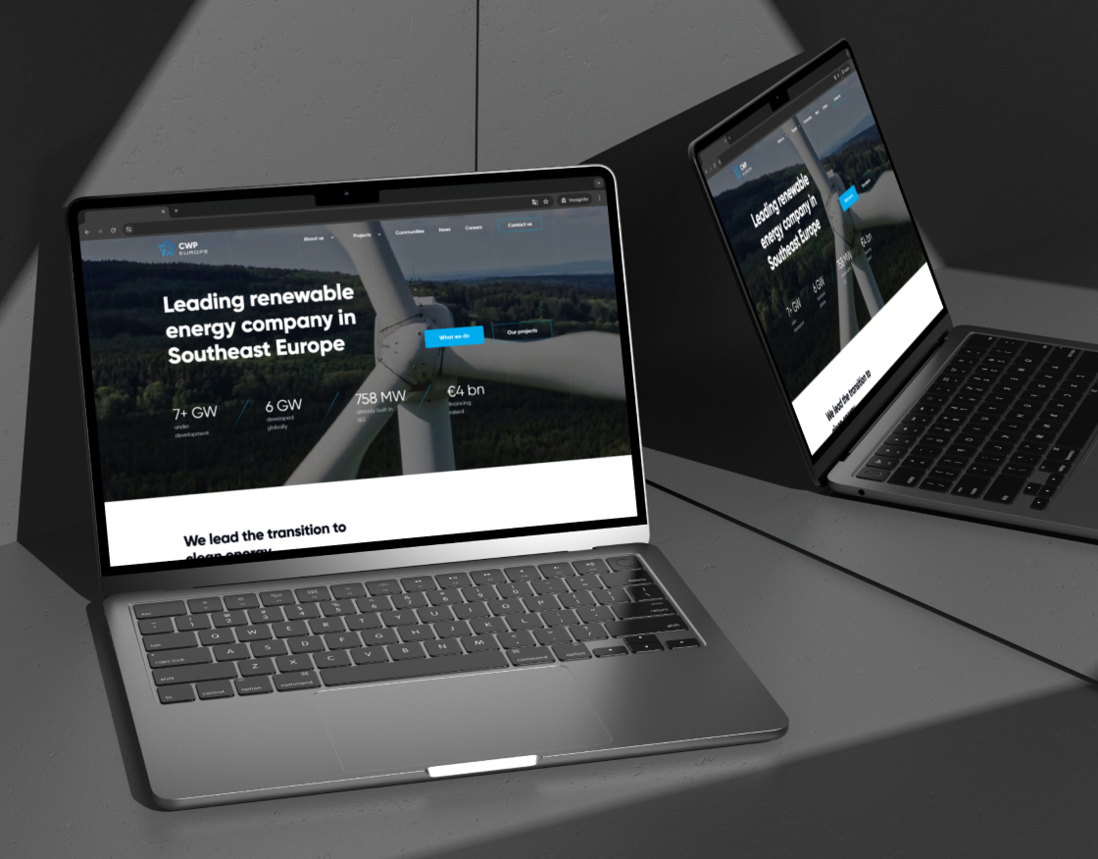 CWP Europe homepage on two laptop mockups in a dark studio setting, wind turbine hero visible on both