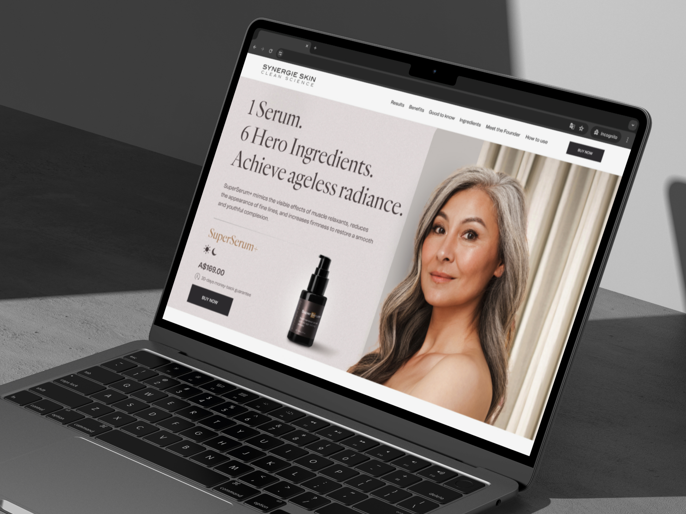 Synergie Skin SuperSerum+ product page shown on a MacBook angled against a grey studio background
