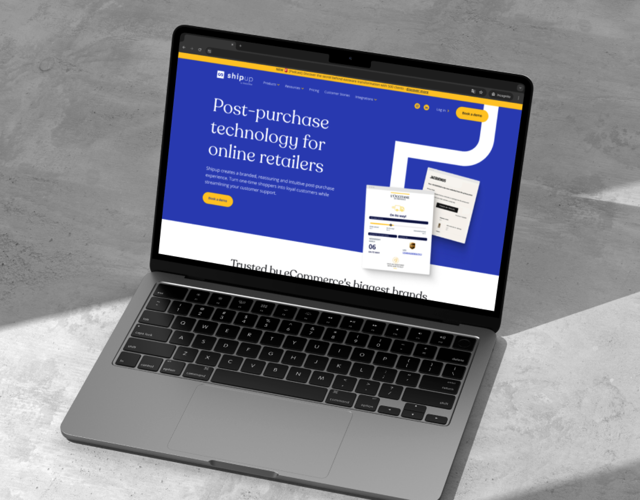 Laptop on concrete showing the ShipUp homepage with its Post-purchase technology for online retailers hero