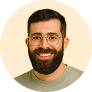 A man with a beard and glasses smiling.