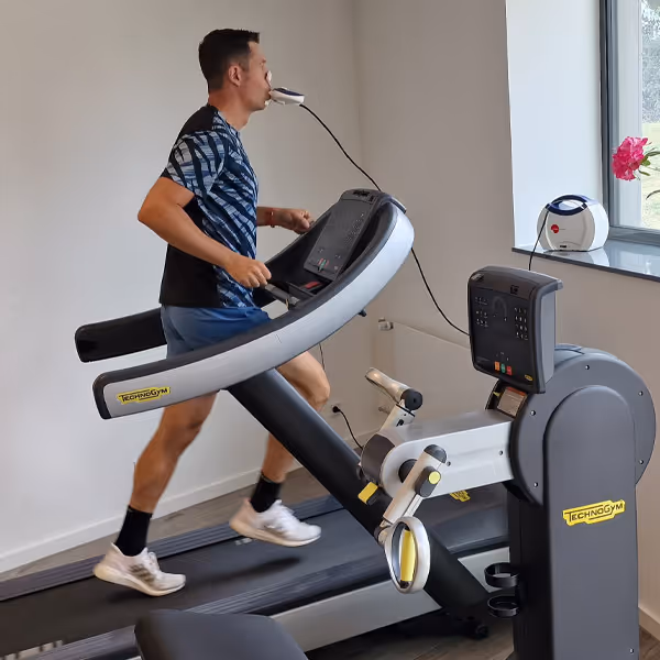 Ole Nauert, Inhaber und Therapeut der Rheinblick Physio, demonstriert eine Gesundheitsanalyse auf dem Laufband im Trainingsbereich der Rheinblick Physio. Hierzu atmet er durch ein Mundstück zur Atemgasanalyse.