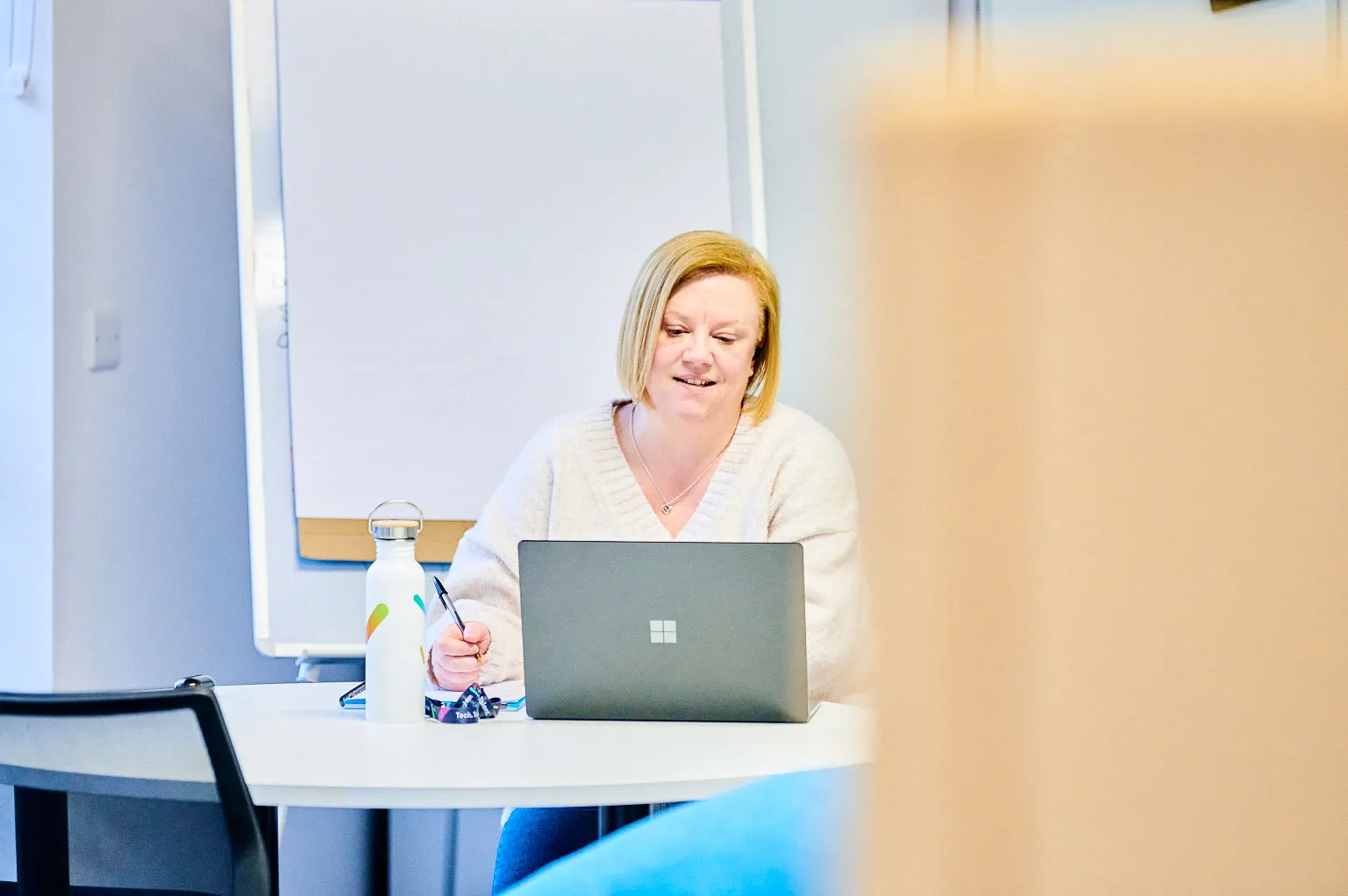 A colleague sitting in front of a laptop, diligently taking notes.