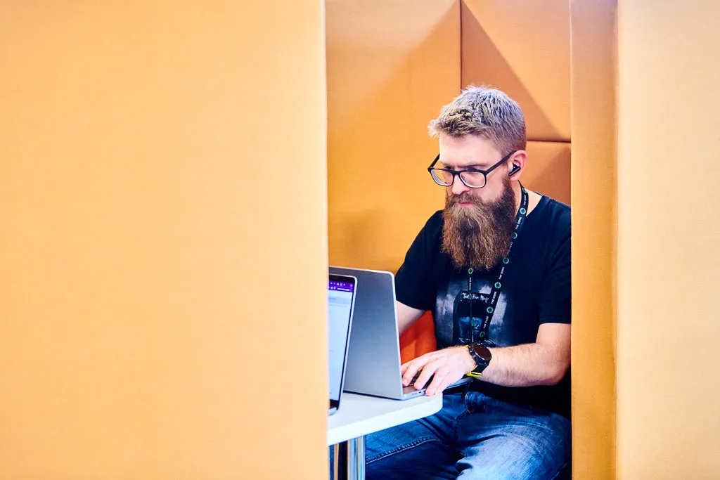 Two members collaborating and exchanging ideas in a quiet booth space.