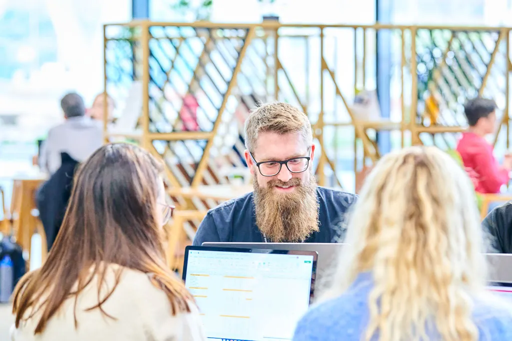 Colleague smiling while working with the team in a cafe.