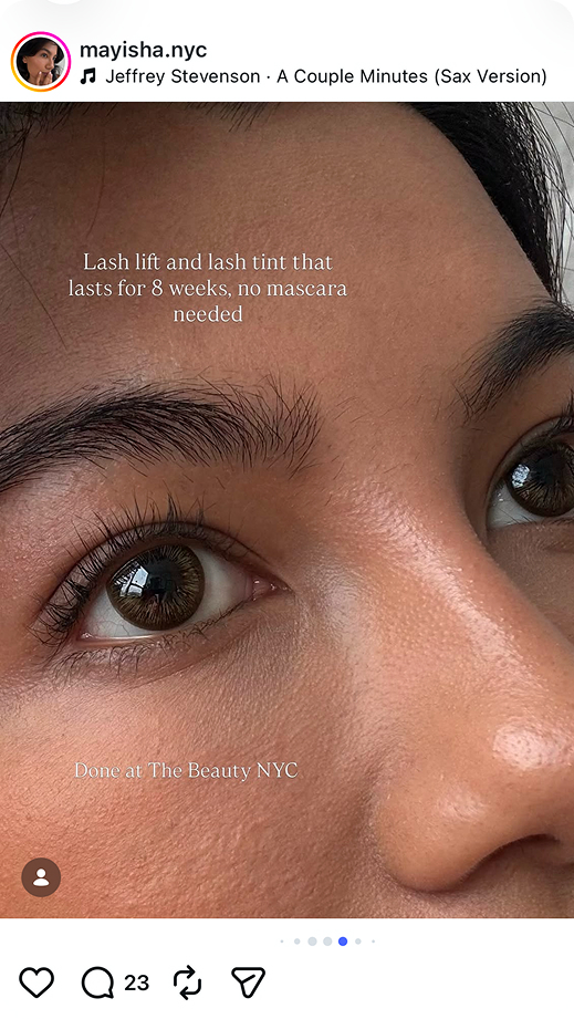 Close-up of a woman with laminated brows and lifted, tinted lashes lying down, smiling gently.