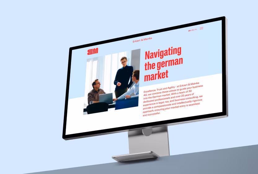 Computerbildschirm zeigt eine Webseite von Erkiert & Mainka mit dem Titel ‚Navigating the german market‘ und einem Bild von drei Personen in einem Geschäftstreffen.