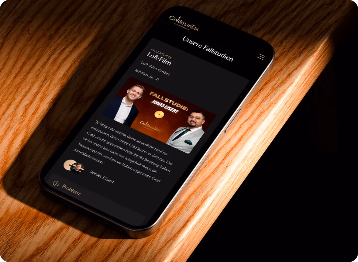 Smartphone zeigt eine Webseite von GoldmanTax mit einer Fallstudie zur Loft-Film GmbH, inklusive Fotos von zwei Männern, Namen Jonas Eisert und einem Zitat zur steuerlichen Struktur.