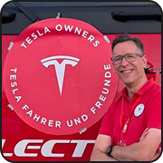 Lars Hendrichs, board member of Tesla Fahrer und Freunde e.V., in front of the red club logo.
