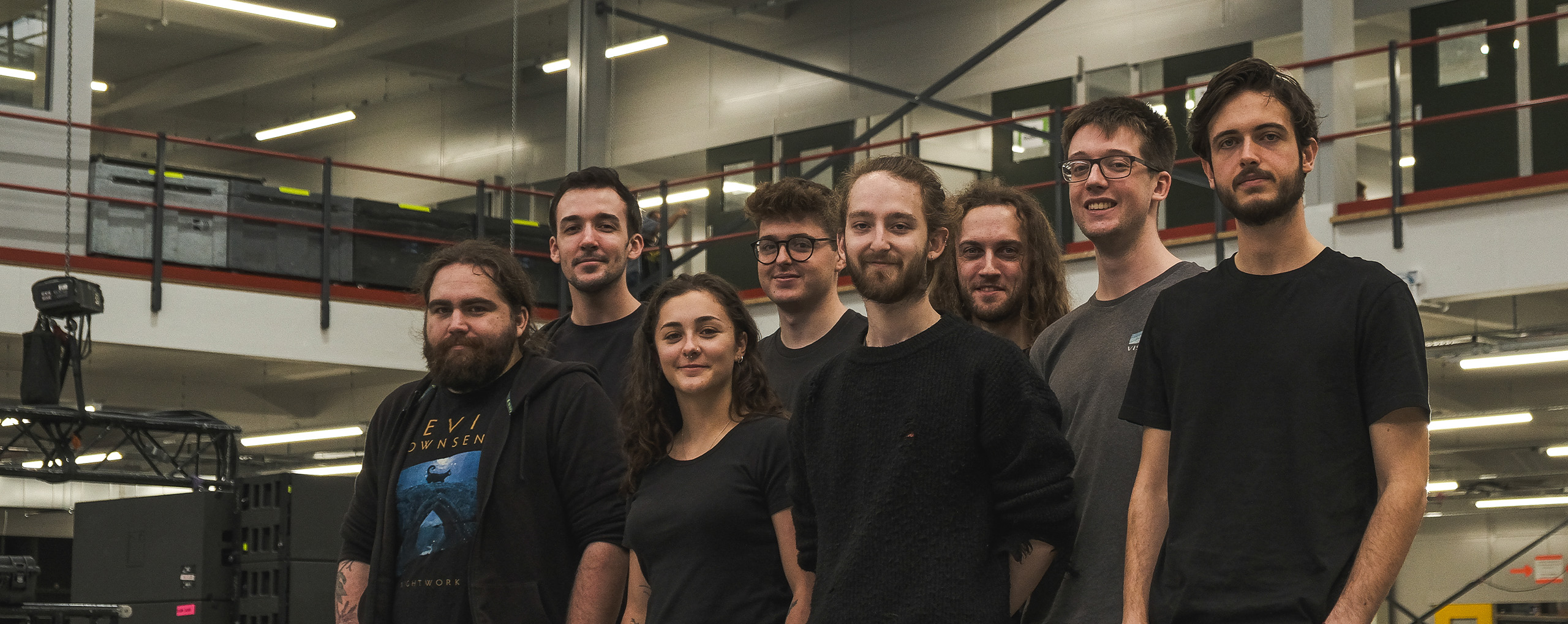 A group of men and women in black t shirts standing in a warehouse