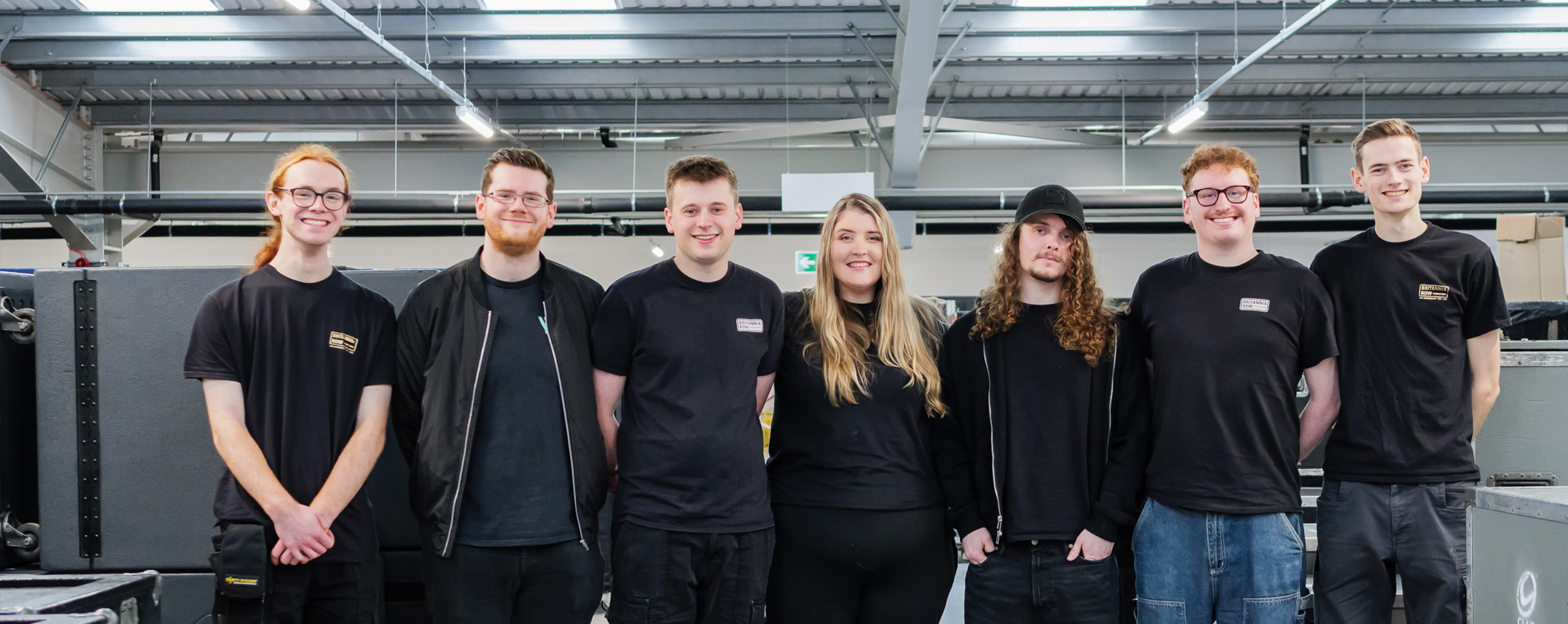 A group of Britannia Row apprentices standing in the warehouse next to grey road cases