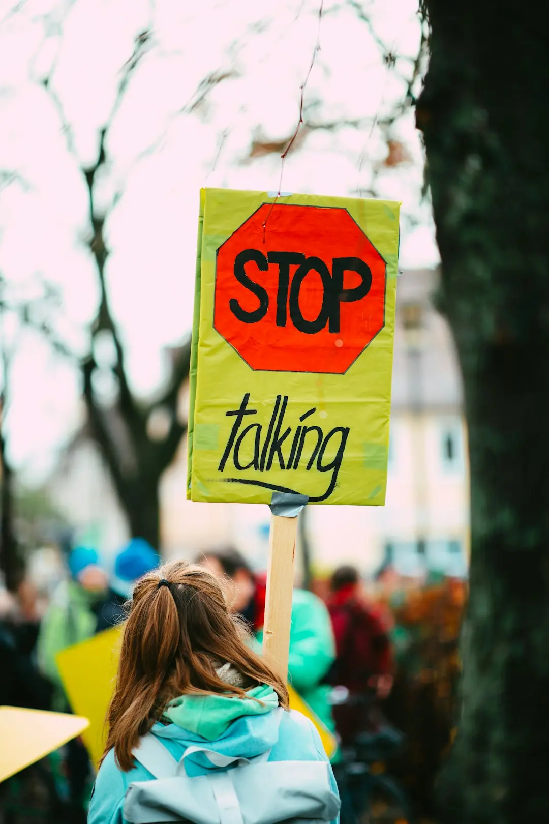woman holding a sign that says "stop talking"