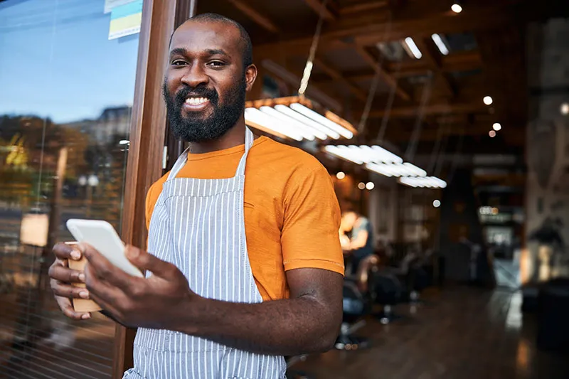 Barbershop owner using booking software on a phone.