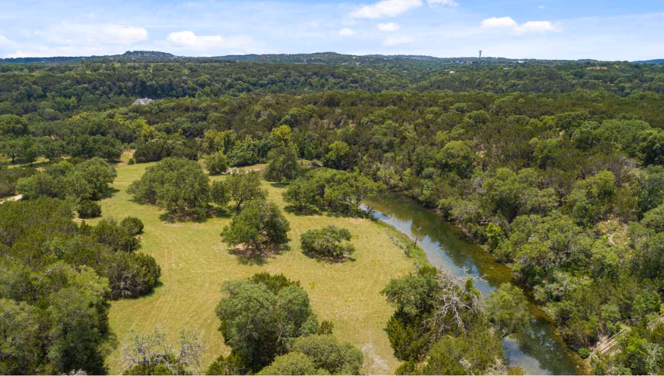 Aerial photo of a Texas hill-county properly with a forest and a river running through it
