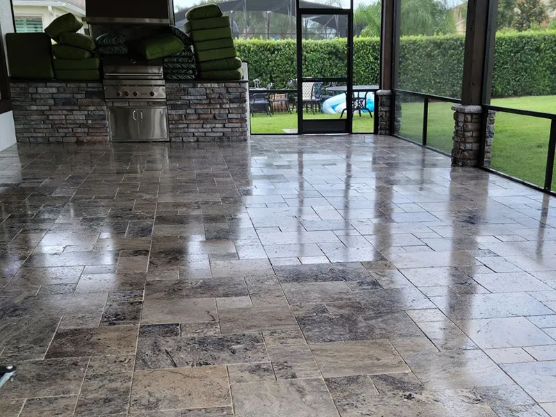 an outdoor kitchen area with a travertine floor and a grill