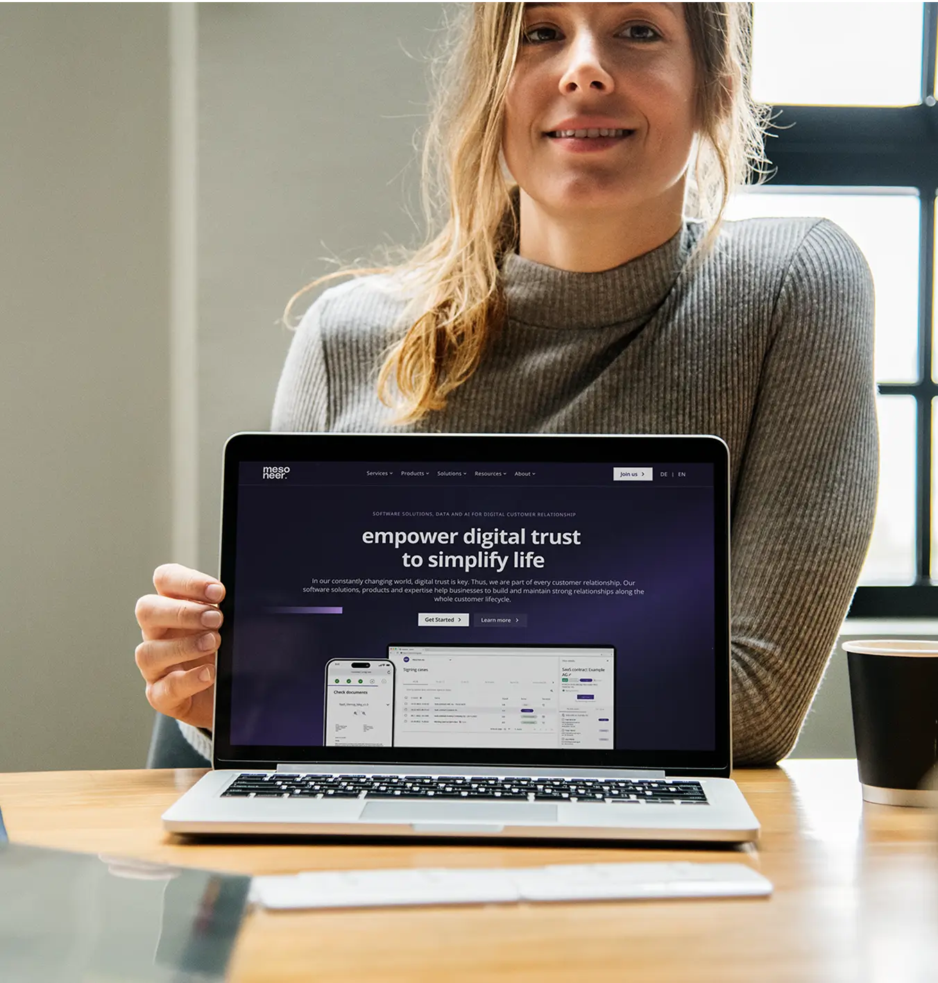 Happy young woman showing the mesoneer website on a laptop.