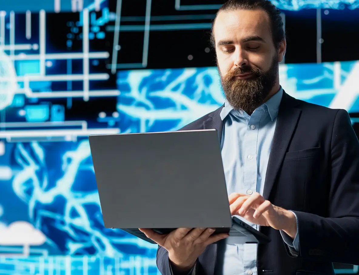 Man with beard in a suit using a laptop against a background of digital data graphics.