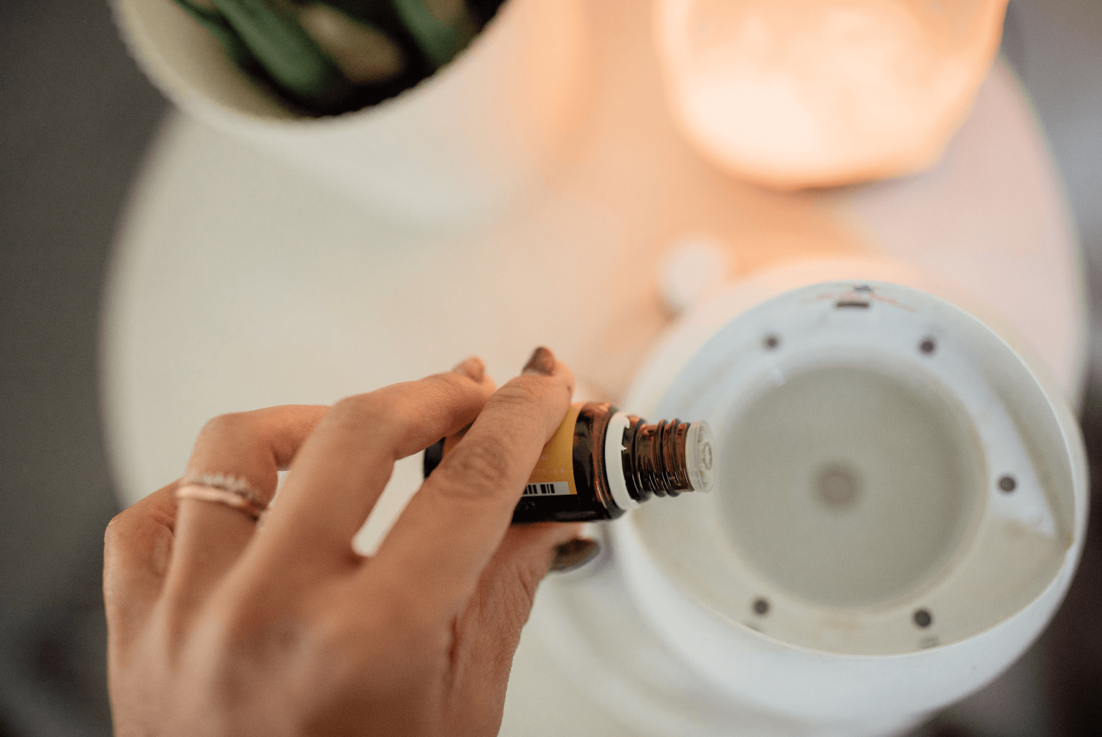 Close-up of woman's hand pouring essential oil into a diffuser