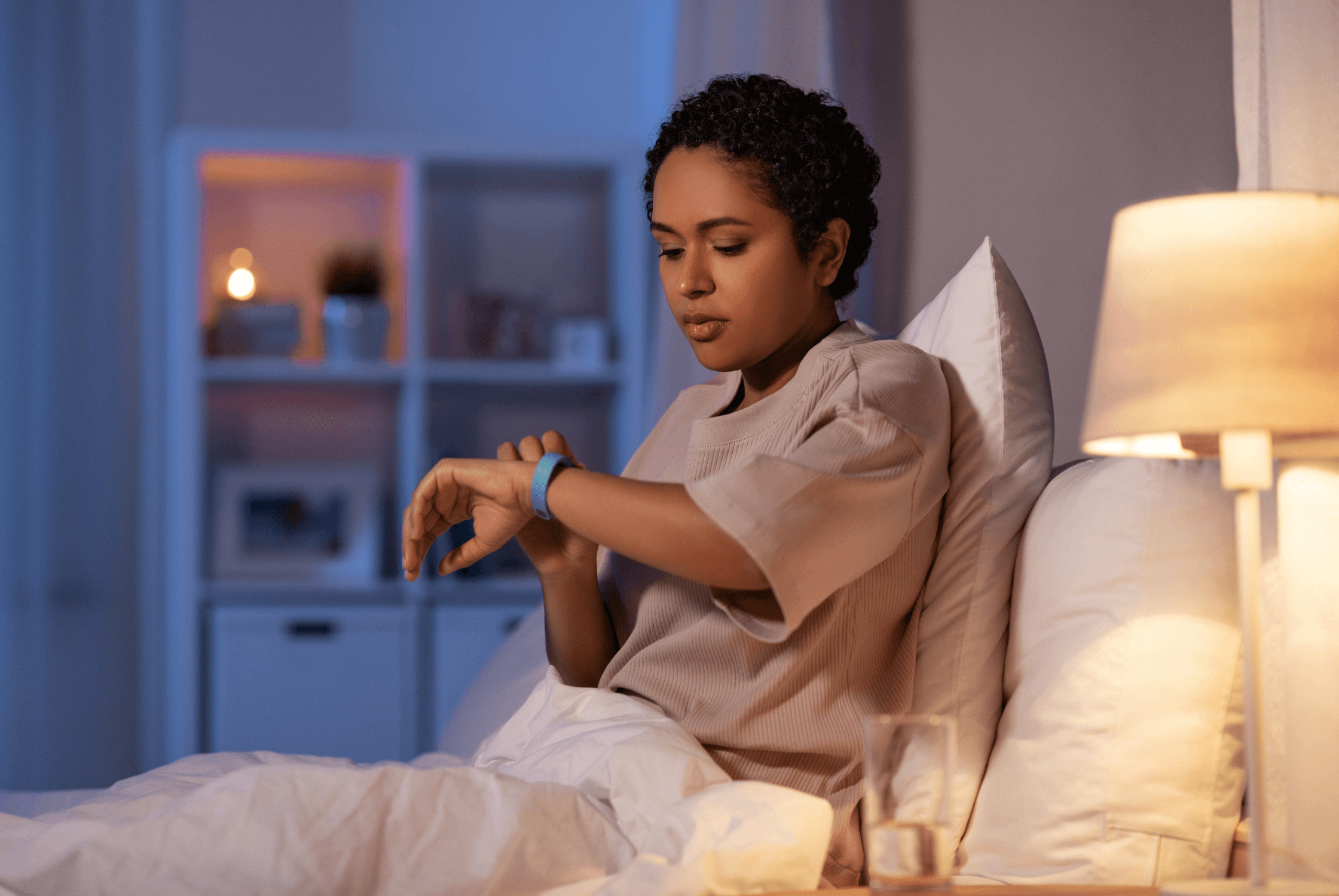 Woman in bed checking sleep tracker watch