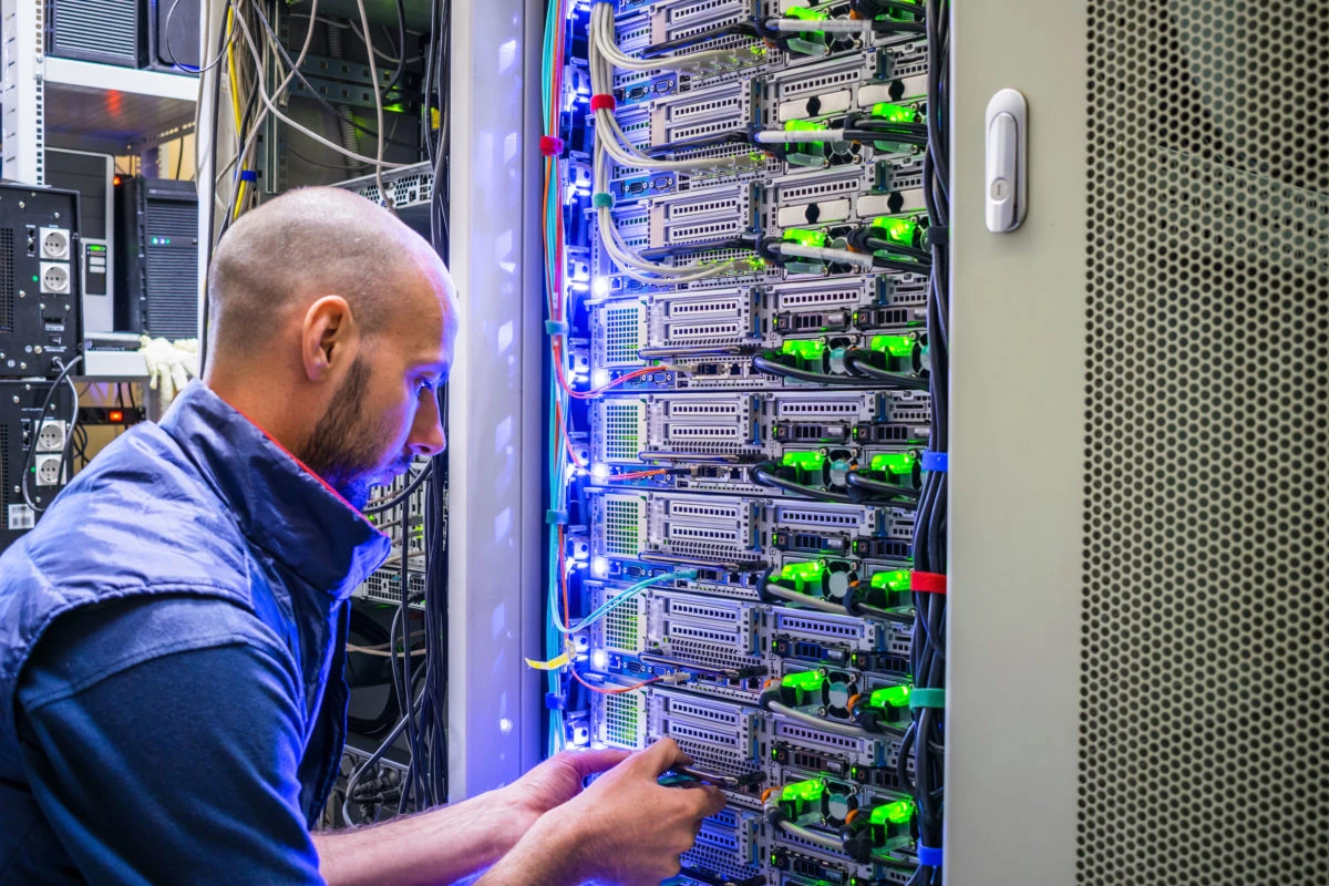 Ein Mann der sich um die Verkabelung bei einem Server kümmert