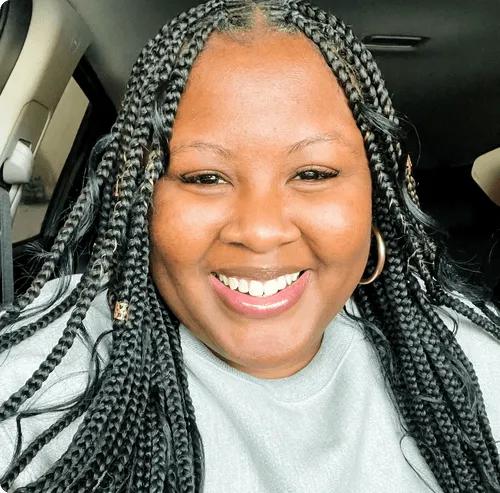 a woman with braids smiling in a car