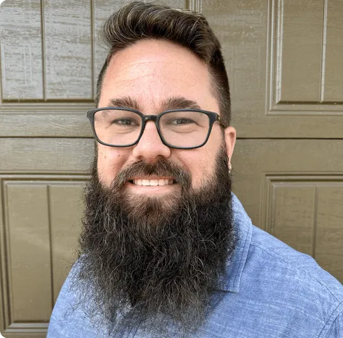 a man with a beard and glasses smiling